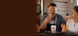 Wendy's commercial screenshot: Wendy's employee sitting at table eating French Toast Sticks with his mom